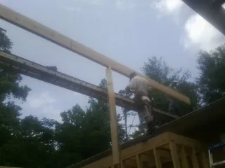 Carpenter setting a ridge beam over a new addition frame — Ice Dam Removal by Roofing Brothers in Roby