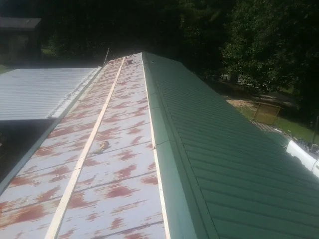 Old rusted panels beside newly installed green metal roofing — Wind Damage Roof Repair by Roofing Brothers in Roby
