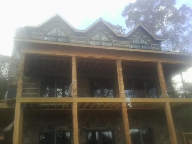 Dormers and porch framing on a large log home under construction — Roof Coating work by our crew in Roby