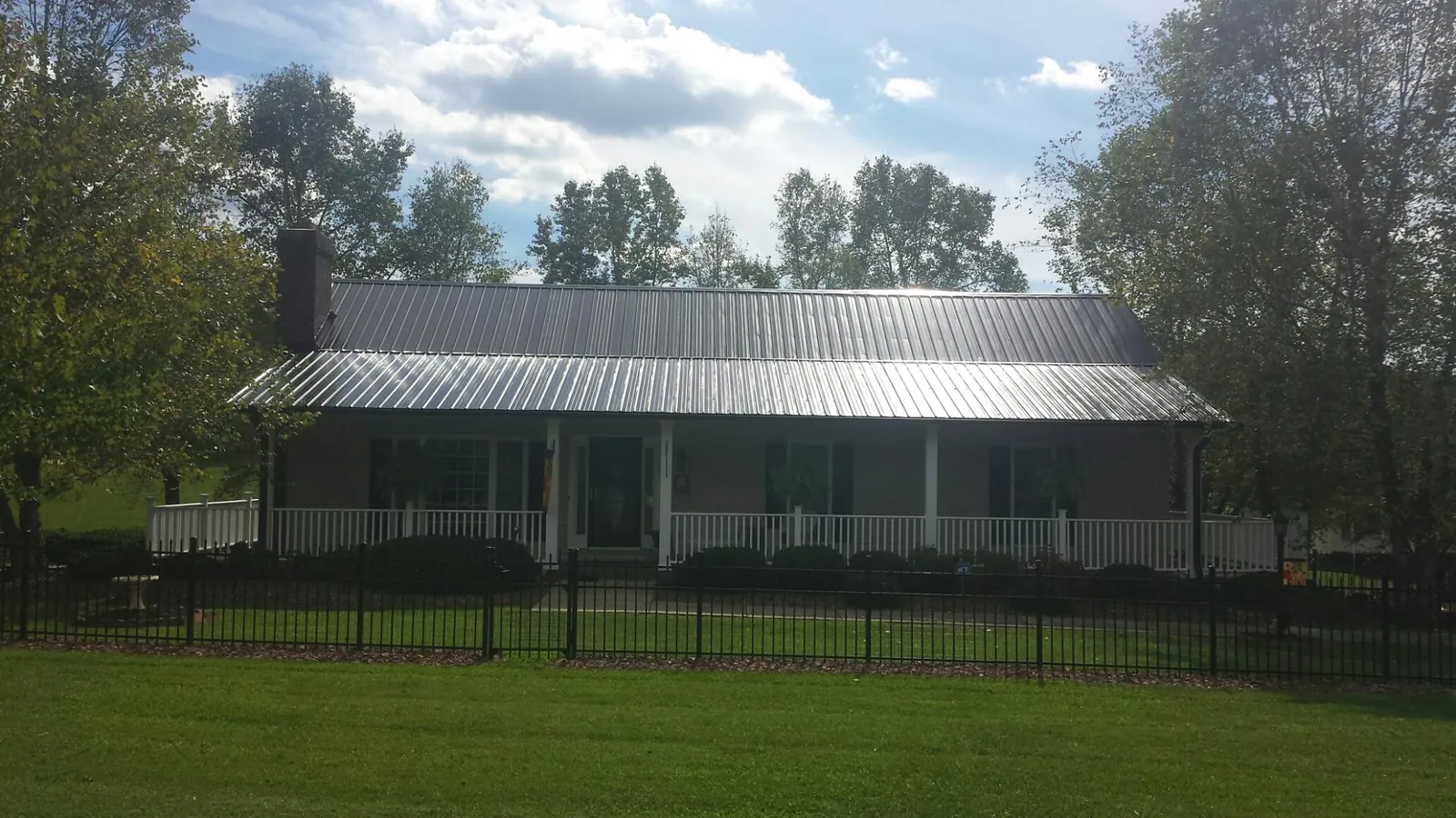 Gray metal roof on a brick ranch with a full width front porch — Gutter Guard Installation work by our crew in Roby