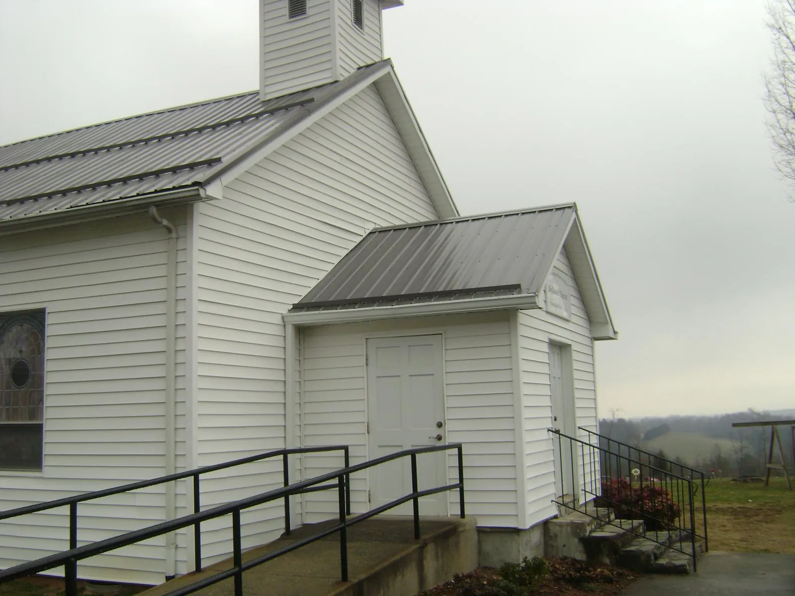 Gray metal roof on a white clapboard church with a steeple in Roby