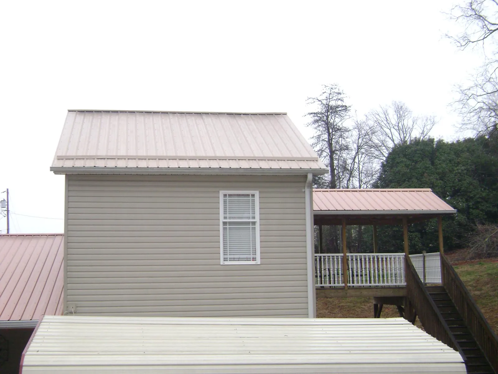 Tan metal roofs on a two story addition and attached porch, from a Roof Replacement job in Roby