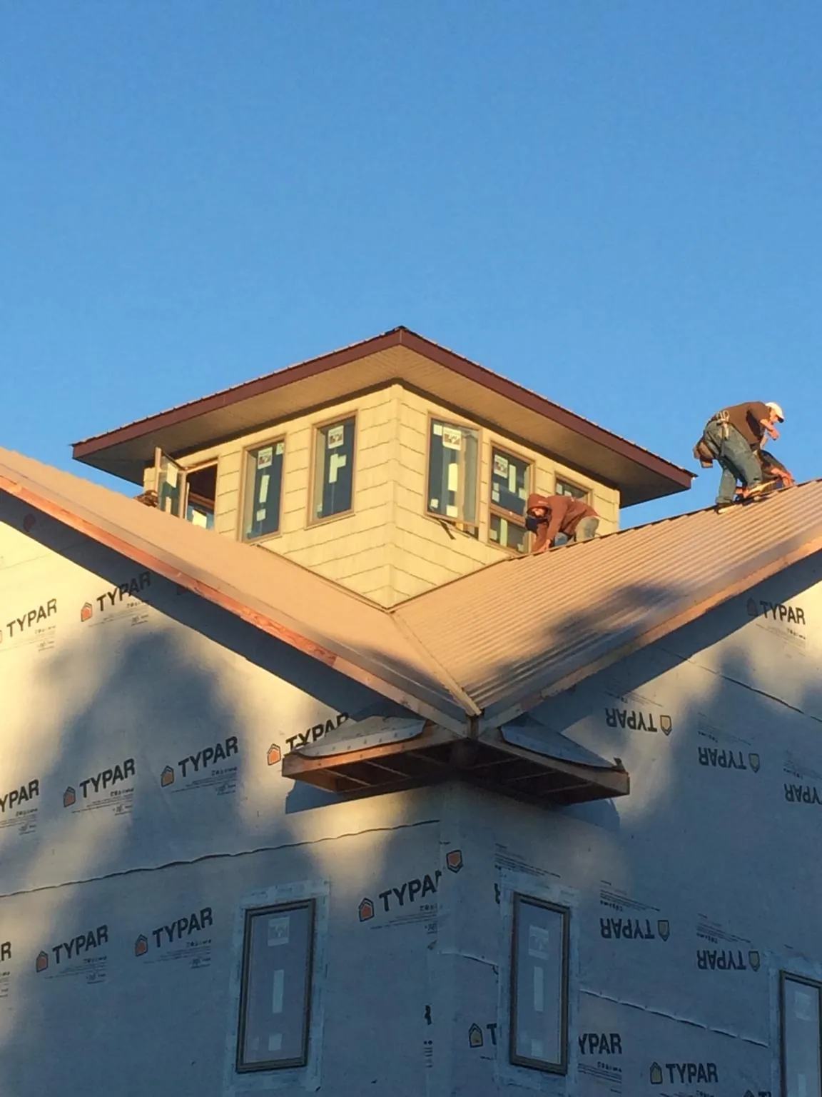 Roofers working around a rooftop cupola on a new metal roof at sunset — Roof Waterproofing in Roby by Roofing Brothers